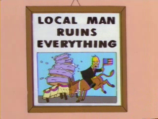 A framed image of Homer Simpson riding backwards on a donkey, holding an American flag, as they crash into a giant cake. A headline says "LOCAL MAN RUINS EVERYTHING."